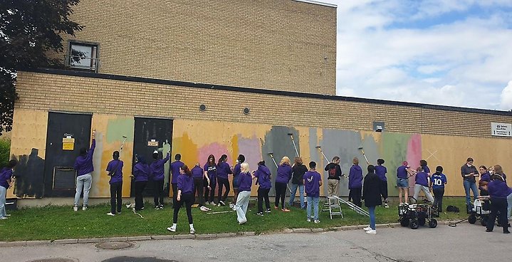 Massor av ungdomar som målar väggen på E:on huset