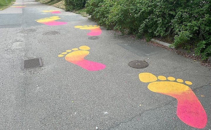 Målade fötter på asfalten i rosa och gult 