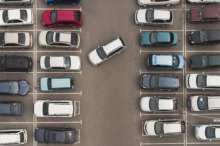Bild på parkeringsplats med en bil som håller på att parkera