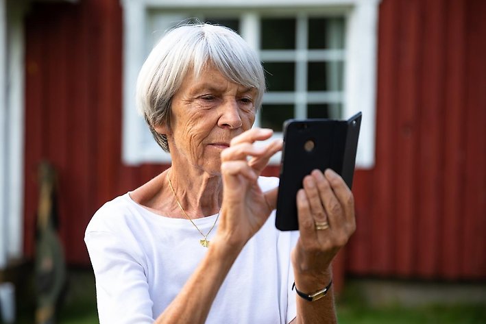 Foto på äldre kvinna som använder mobiltelefon.