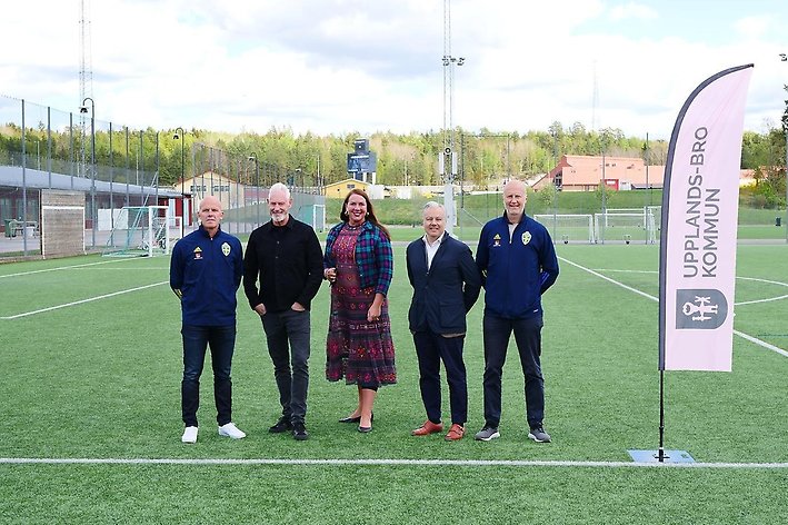 Representanter från Svenska Fotbollförbundet och Upplands-Bro kommune står på rad på en fotbollsplan och tittar mot kameran