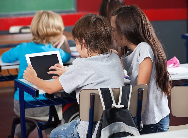 Barn i ett klassrum med en lärplatta i handen