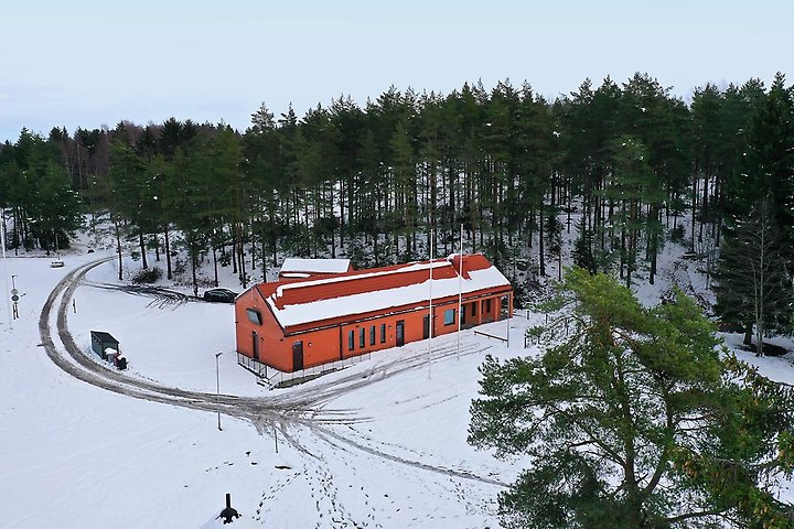 Flygbild över en röd tegelbyggnad omgiven av snö.