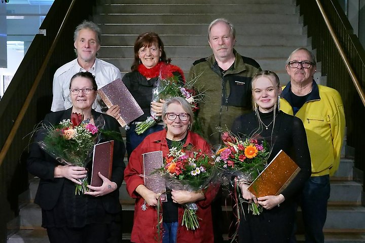 En grupp personer som håller i blommor efter att ha fått stipendier